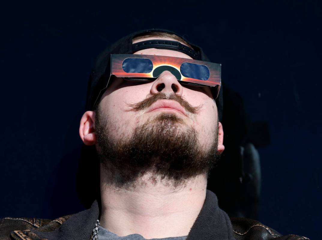 Logen Swartley watches a partial solar eclipse at the observation deck at The Strat on Monday, ...