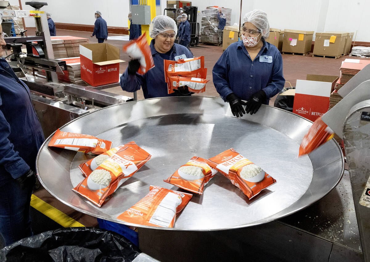 Workers gather up bags of Netflix cheddar-flavored popcorn at Eagle Foods manufacturing facilit ...