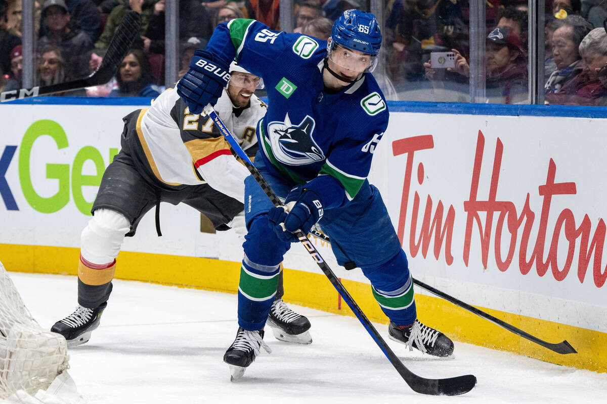 Vegas Golden Knights' Shea Theodore (27) and Vancouver Canucks' Ilya Mikheyev (65) vie for the ...