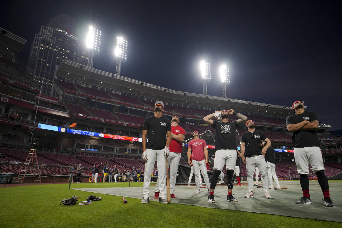 Members of the Cincinnati Reds use special glasses as they watch the solar eclipse before a bas ...