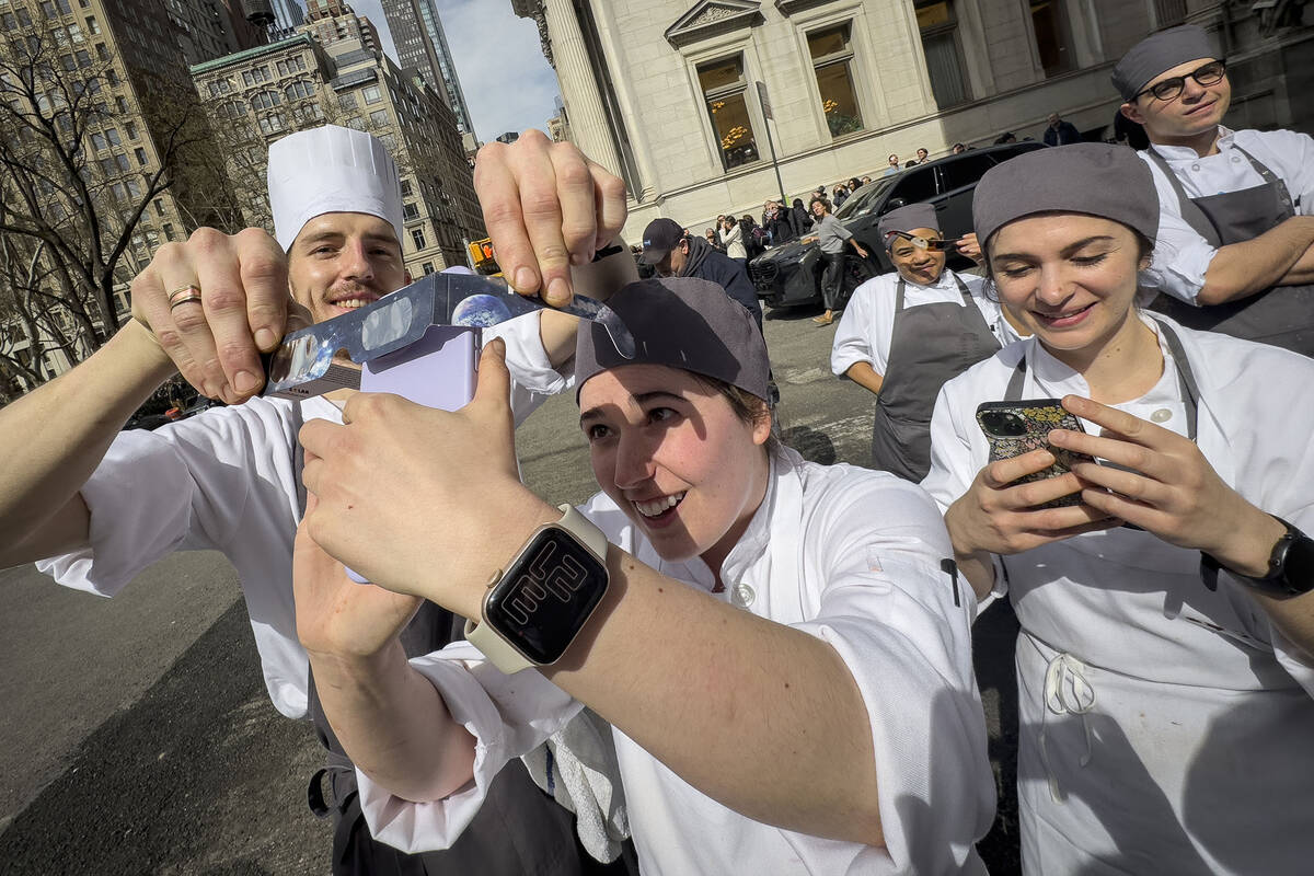 Restaurant workers in the Flatiron district of Manhattan take a break to view the solar eclipse ...