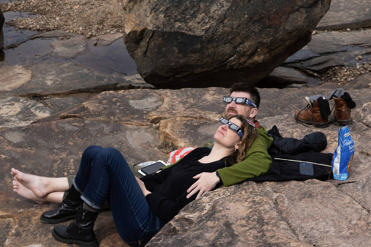 Ian Morris and Allyson Gavaletz use special glasses to watch the total solar eclipse from Agers ...