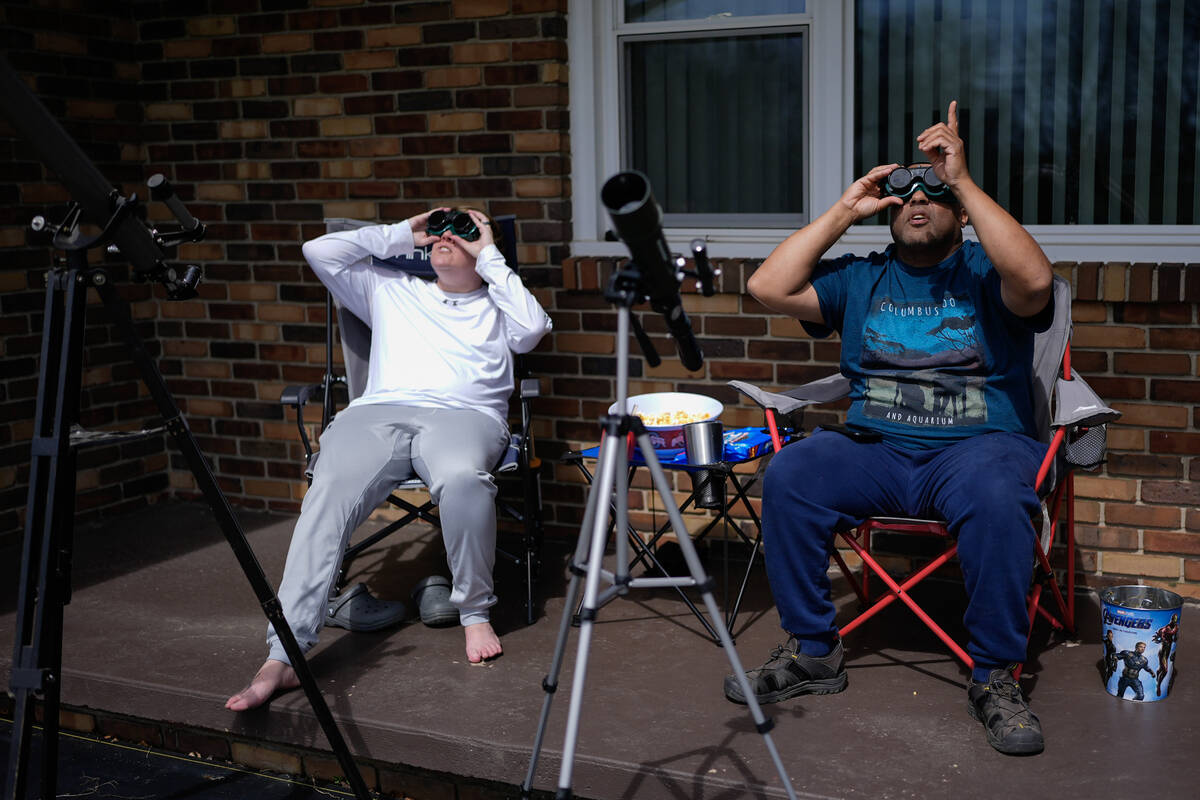 Melissa, left, and Michael Richards watch through solar goggles as the moon partially covers th ...