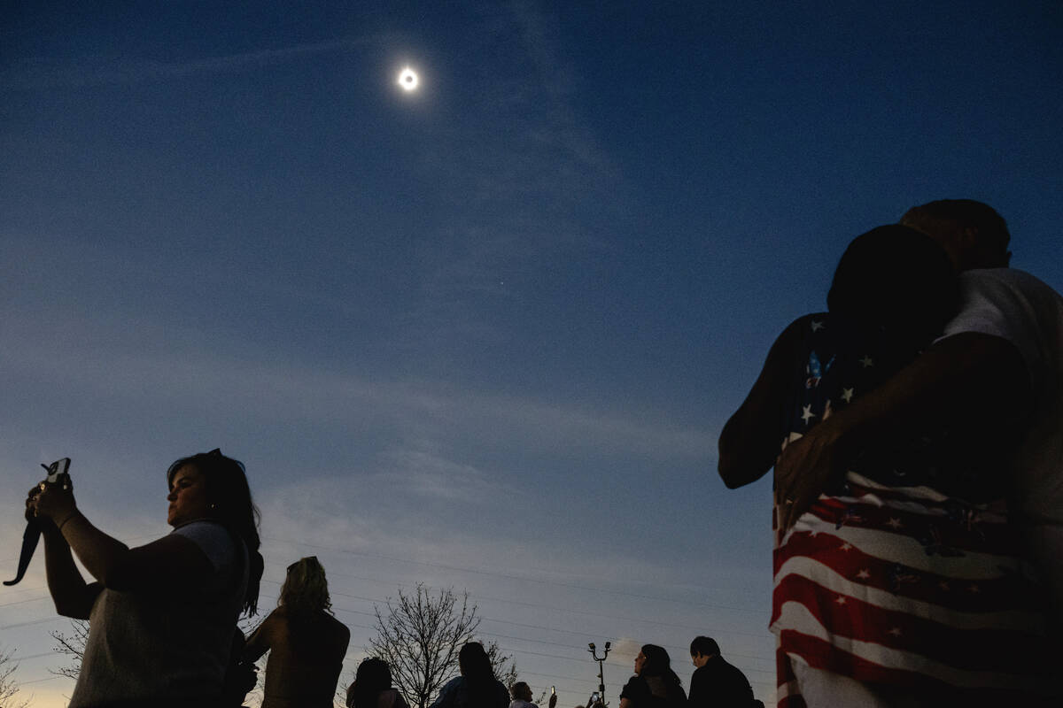 Newly wed couples look up at a total solar eclipse during a mass wedding ceremony at Trenton Co ...