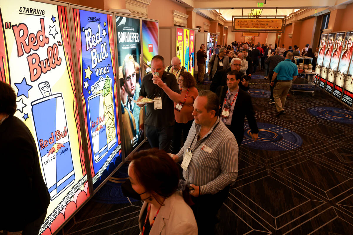Conventioneers walk past movie posters and advertisements at the CinemaCon trade show at Caesar ...