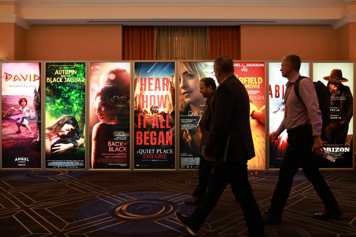 Conventioneers walk past movie posters at the CinemaCon trade show at Caesars convention center ...