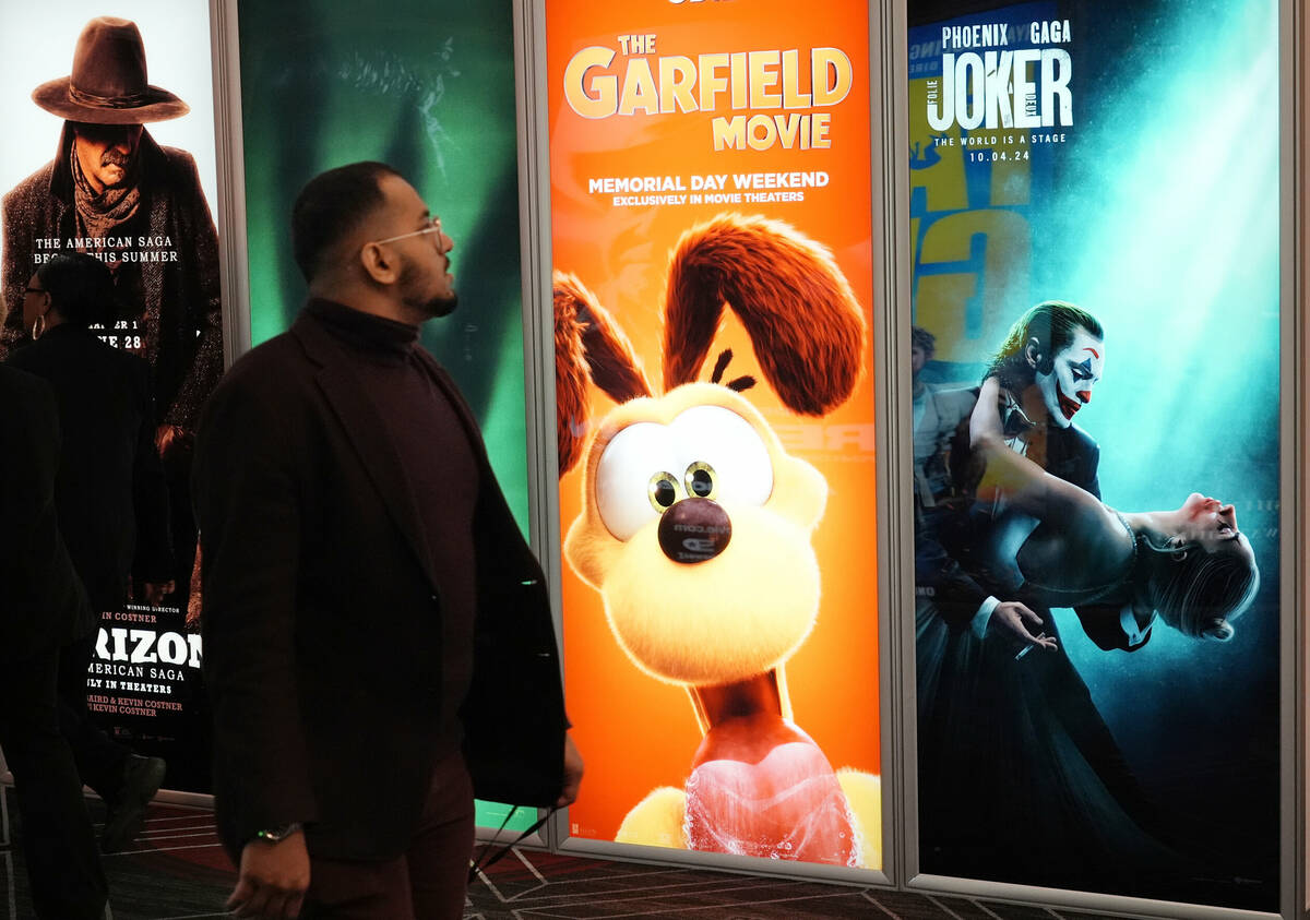 An attendee walks past advertisements for upcoming films, including "The Garfield Movie" and "J ...
