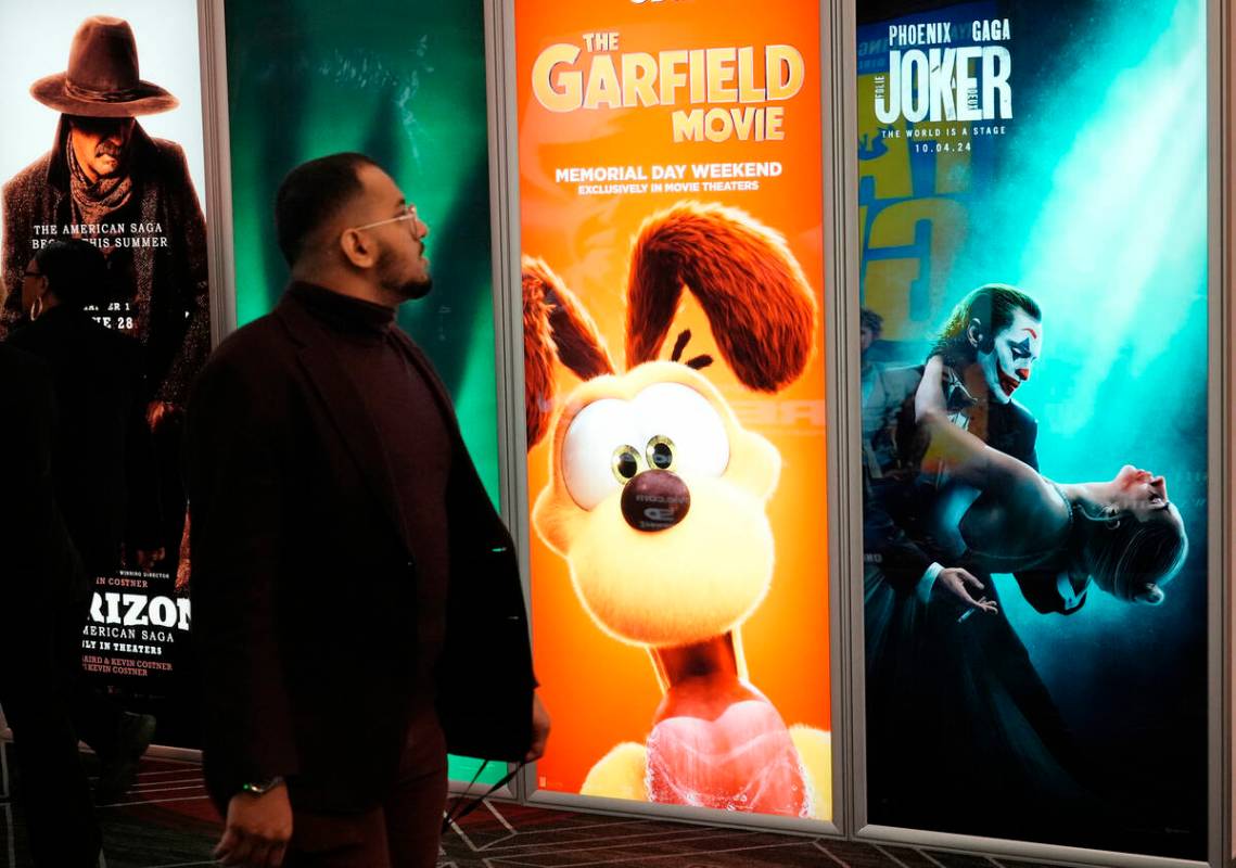 An attendee walks past advertisements for upcoming films, including "The Garfield Movie" and "J ...