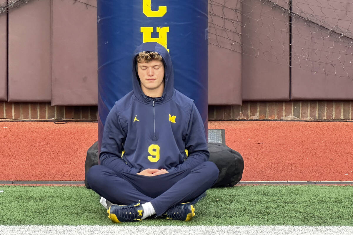 Michigan quarterback J.J. McCarthy sits on the field with his back against a padded goalpost on ...