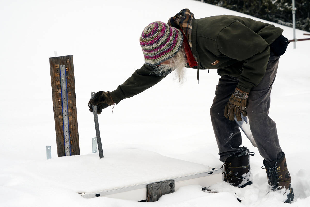 Billy Barr measures the depth of new snow that has fallen onto his snow board Wednesday, March ...