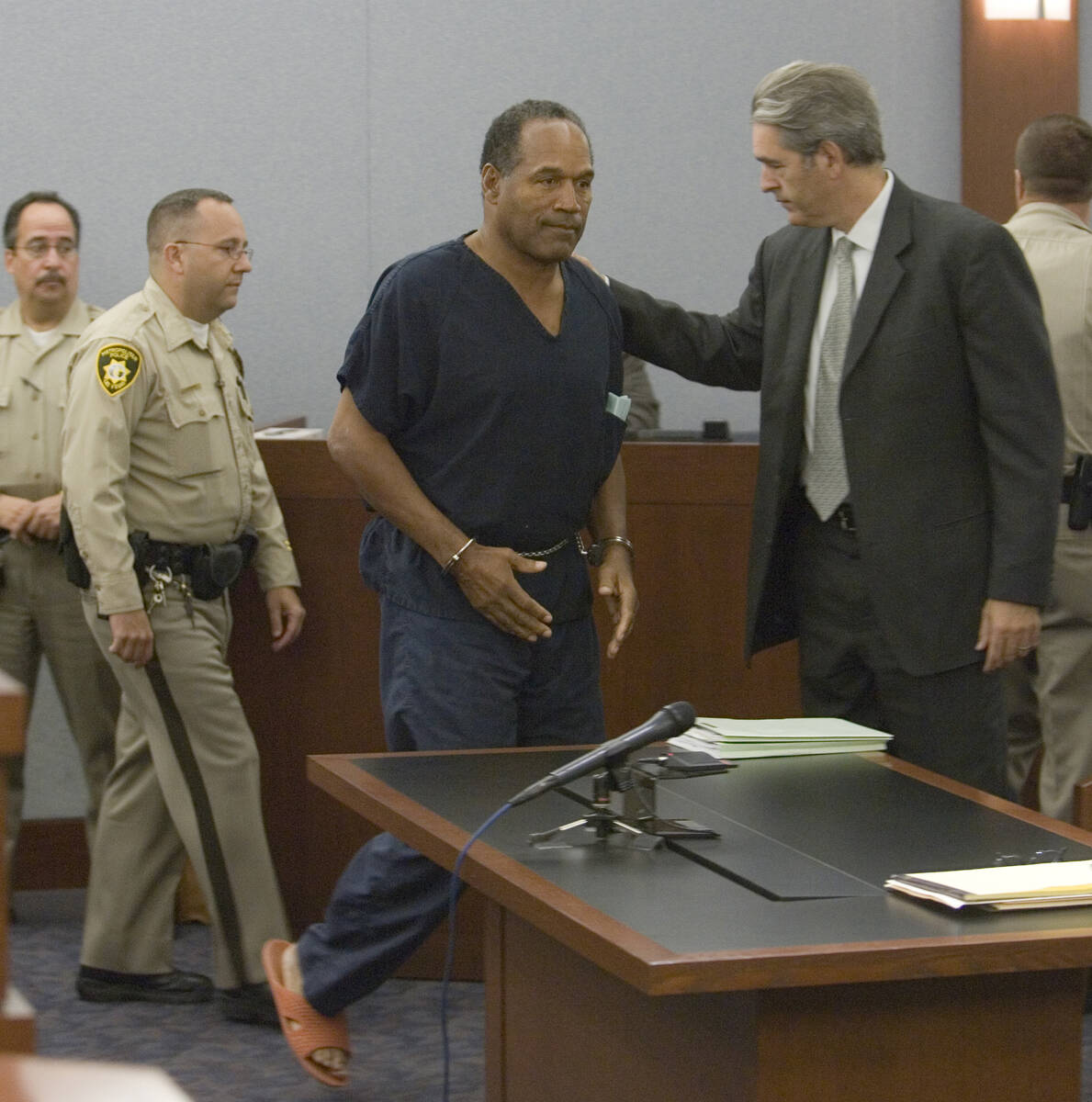 Former NFL player O.J. Simpson, center, is greeted by attorney Gabriel L. Grasso as he is arrai ...