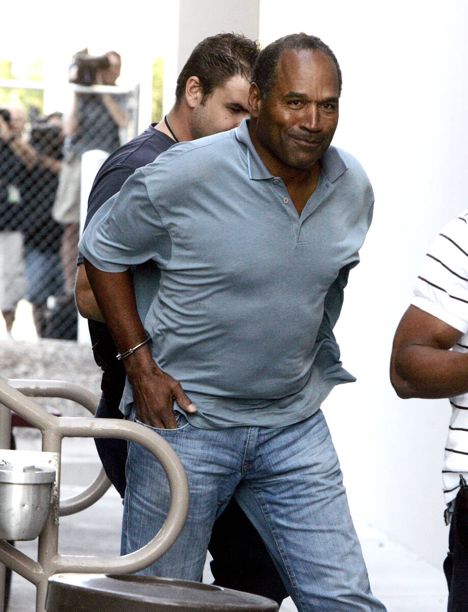 Former NFL football player O.J. Simpson is escorted by Las Vegas police officers from their Inv ...