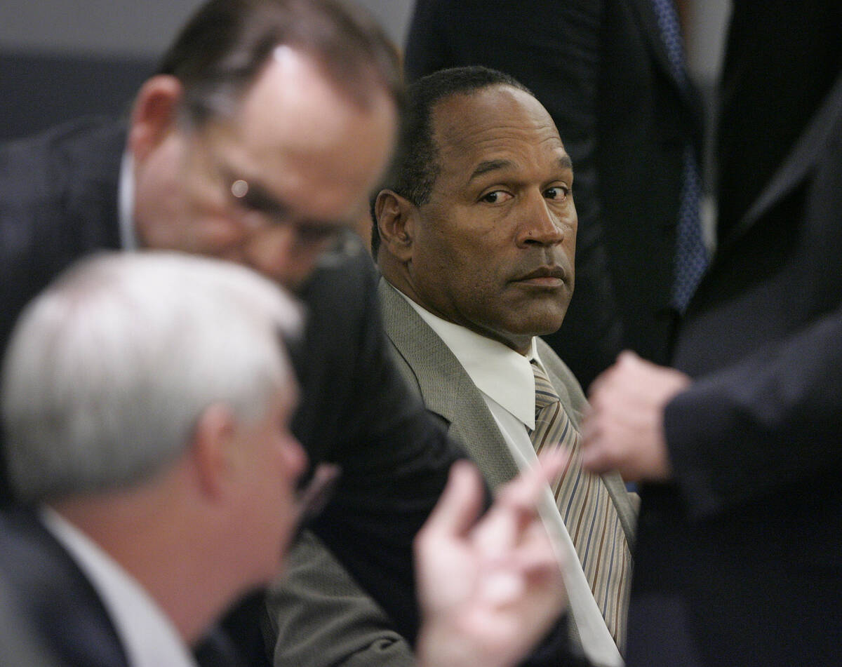 Former NFL great O.J. Simpson, center, watches lawyers confer in court at the Clark County Regi ...