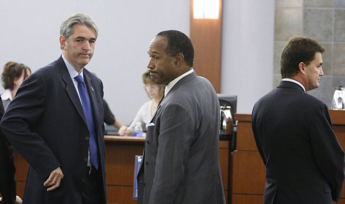 Former NFL player O.J. Simpson is flanked by his attorneys Gabriel Grosso, left, and Yale Galan ...