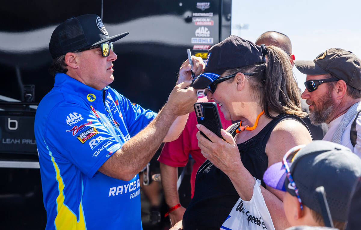 Top Fuel racer Tony Stewart signs autographs in his pit before his first race of the day during ...