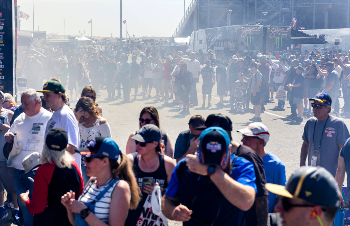 Fans cover up as nitromethane from a top fuel dragster fill the air in the pits during Day 1 of ...