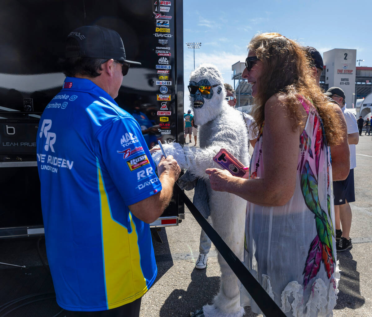 Top Fuel racer Tony Stewart greets a person dressed as a yeti while signing autographs in his p ...