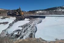 Crews use heavy machinery to place boulders downstream of the cracked Panguitch Lake Dam to rei ...