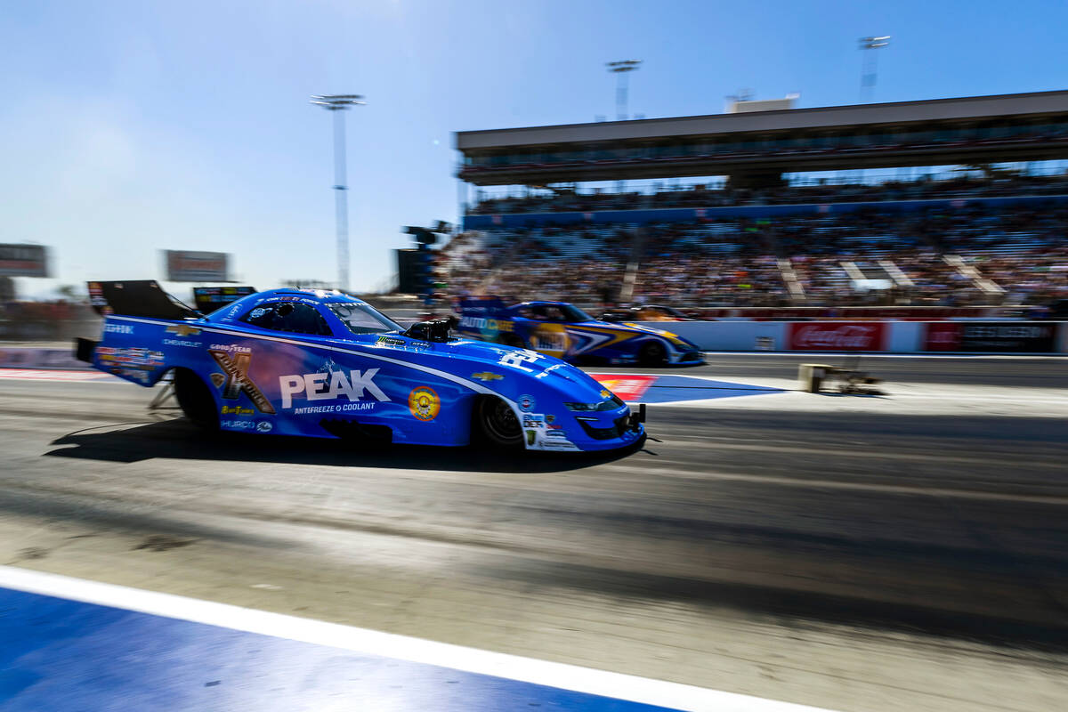 Funny Car driver John Force, near, races beside Ron Capps does a burnout to warm his tires duri ...