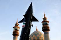 A model of a missile is carried by Iranian demonstrators as minarets and dome of a mosque is se ...