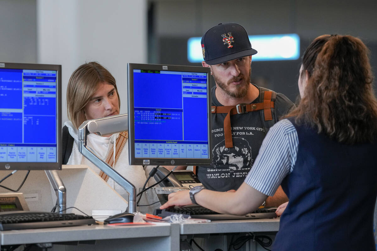 FILE - A airline agents helps a travelers in the departures area of Terminal B at LaGuardia Air ...