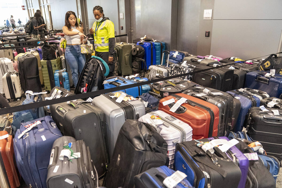 FILE - An airline employee, right, helps a traveler find her suitcase amongst the unclaimed lug ...