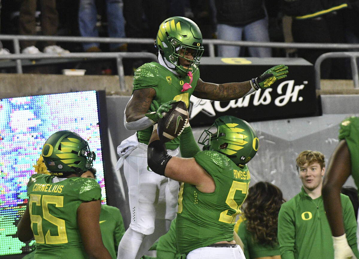 Oregon running back Bucky Irving is hoisted by offensive lineman Jackson Powers-Johnson (58) af ...
