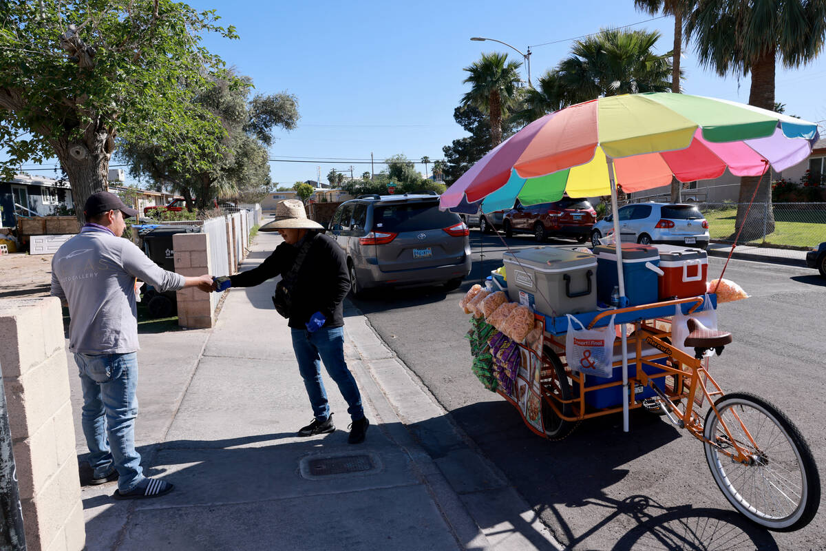 Sidewalk vendor Samuel Gonzalez serves a customer in East Las Vegas Tuesday, April 16, 2024. (K ...