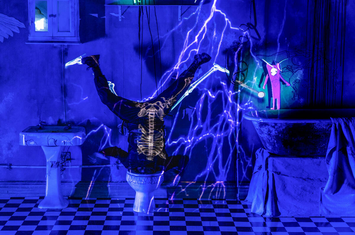 A dancer is struck by lightning while upside down in a toilet as animated imagery are projected ...