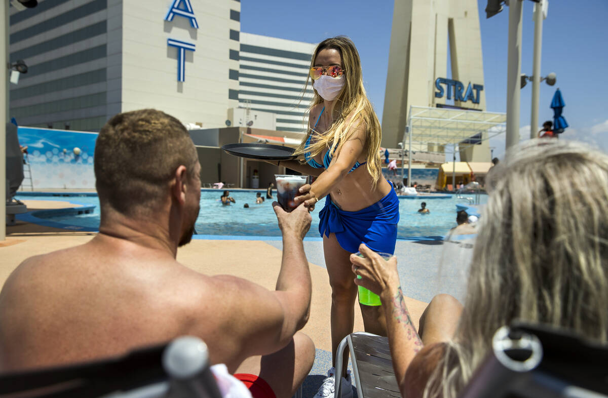 A cocktail waitress serves drinks to guests at the pool at The Strat on Saturday, June 6, 2020 ...