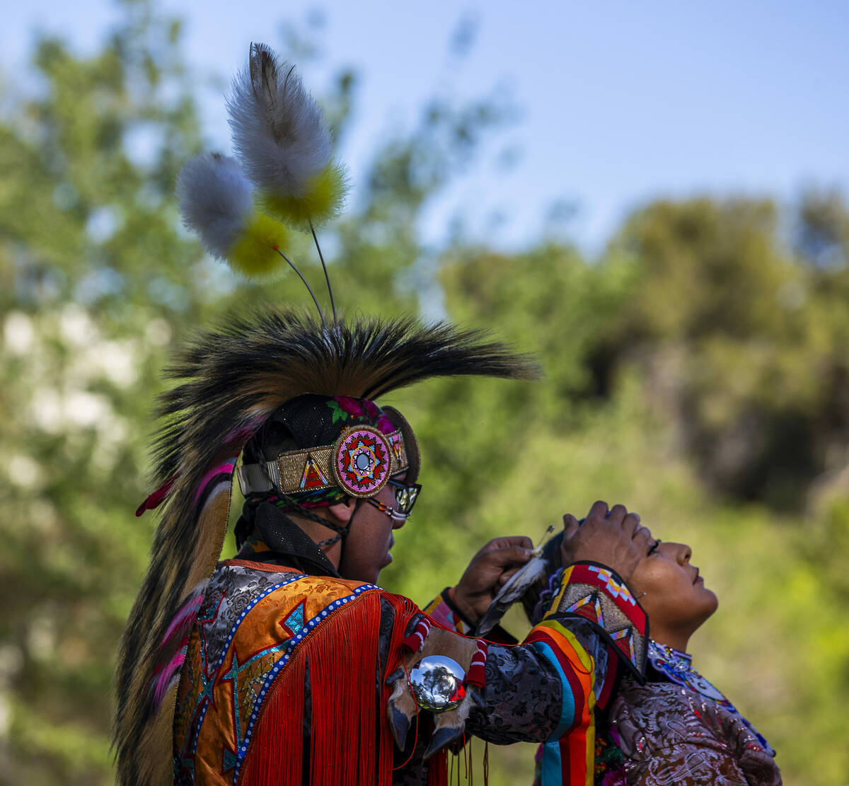 Sal Brown helps Myra Harrison with a feather in her hair, both with the Navajo tribe from Flags ...