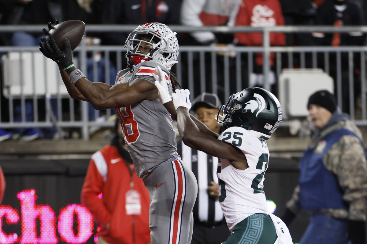 FILE - Ohio State receiver Marvin Harrison, left, catches a touchdown pass over Michigan State ...