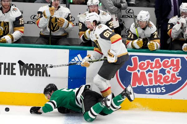 Dallas Stars center Wyatt Johnston, left, falls to the ice attempting to control the puck under ...