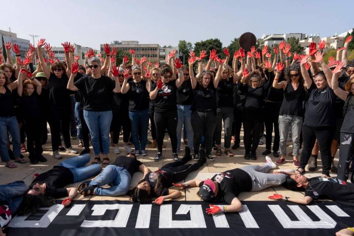 Family and supporters of hostages held in the Gaza Strip hold up their hands, painted red to sy ...