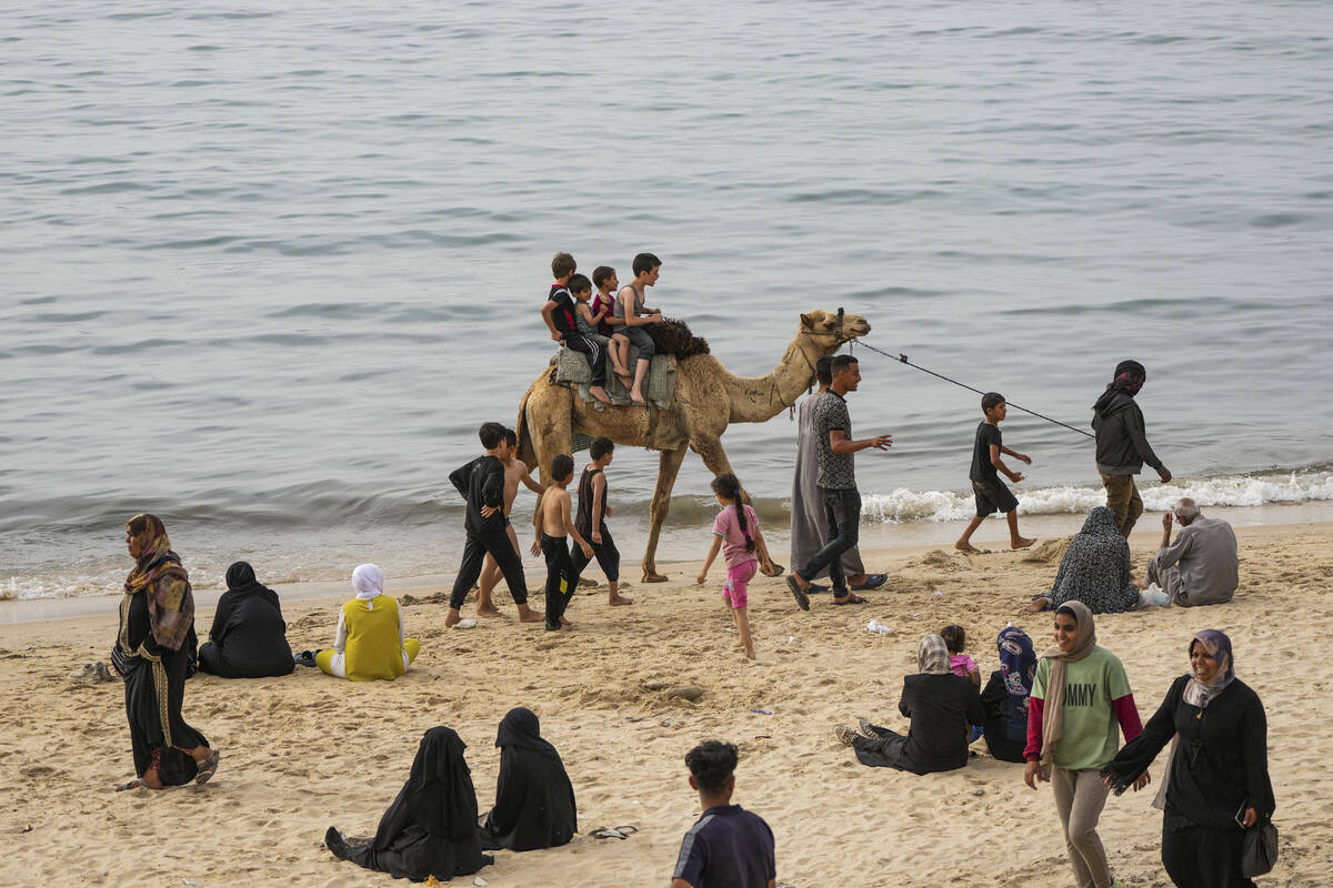 Palestinians spend the day on the beach along the Mediterranean Sea during a heatwave in Deir a ...