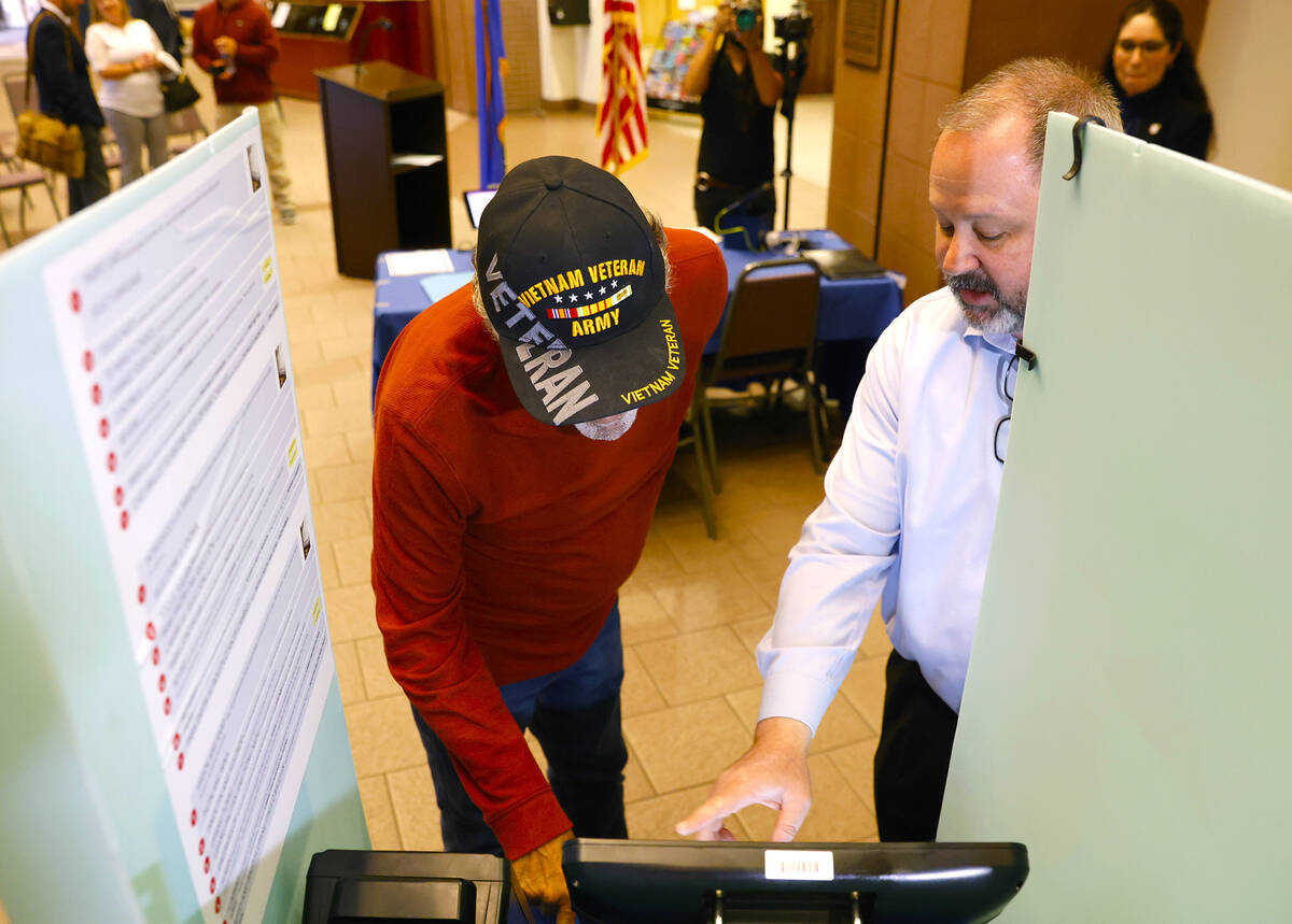 Dan Kulin, right, manager Election Administration, demonstrates how to cast a vote to Pete Pizz ...