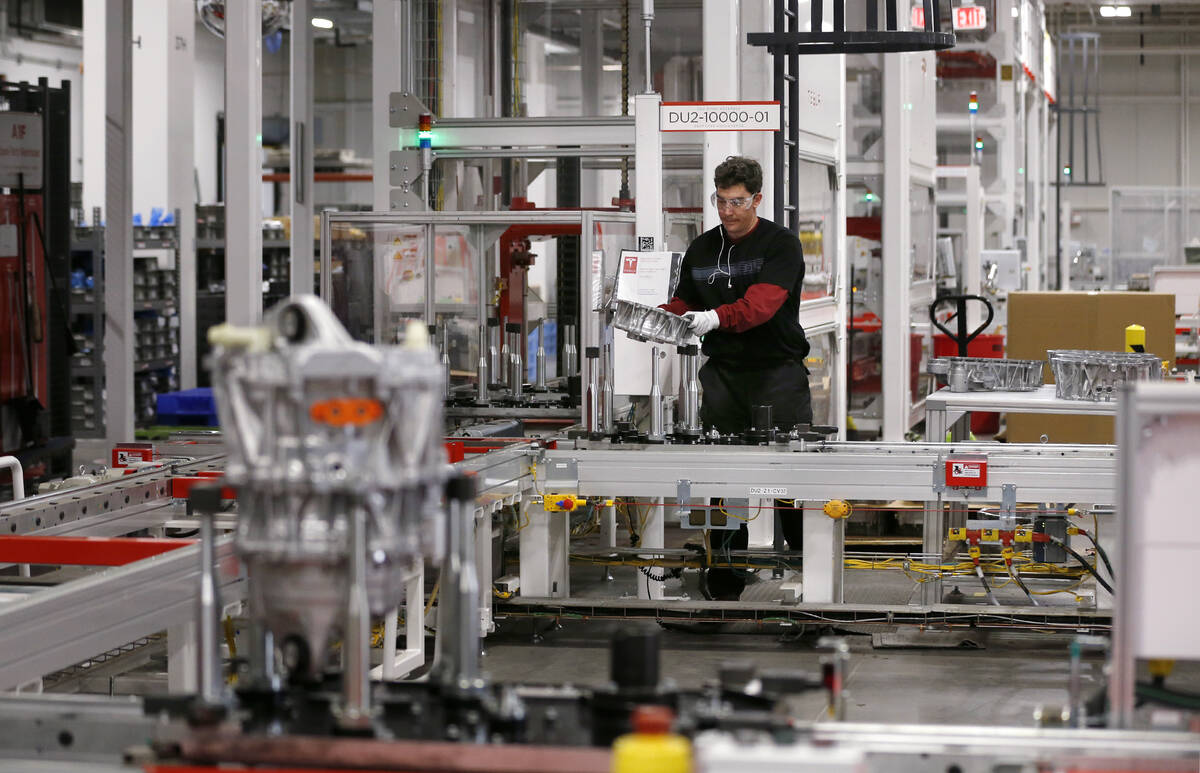 One of many robots loads a completed Model 3 drive unit into a shipping container at the Tesla ...