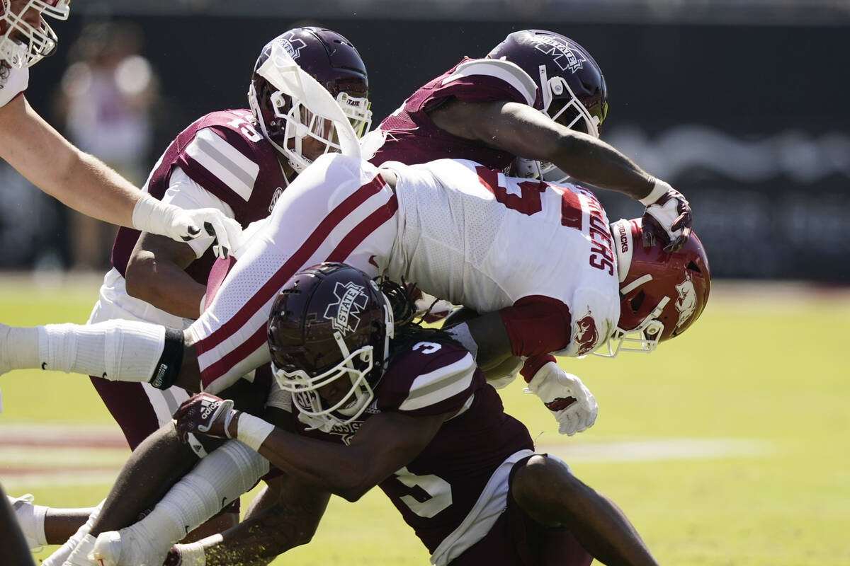 Arkansas running back Raheim Sanders (5) is tackled by a couple of Mississippi State defenders ...