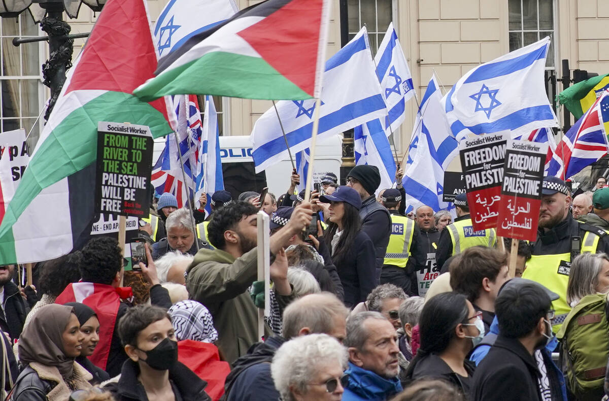 People take part in a pro-Palestine march as they walk past a counter protest with Israeli flag ...