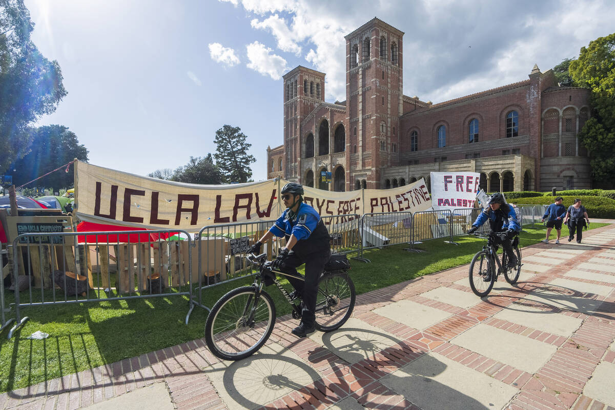 UCLA campus police cycle around the perimeter of a pro-Palestinian encampment on the UCLA campu ...