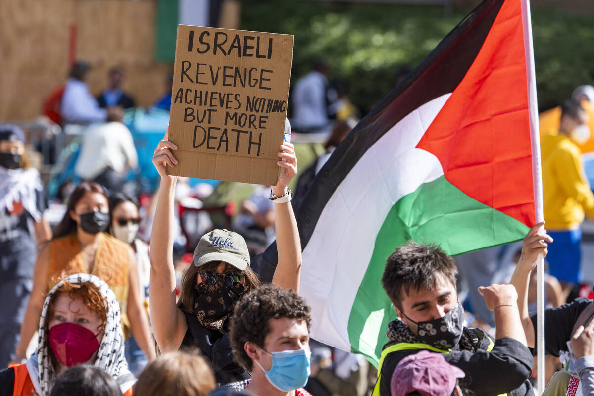 Pro-Palestinian supporters hold up a sign and flag inside an encampment on the UCLA campus Frid ...