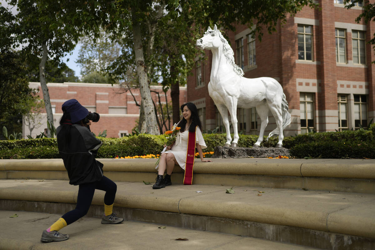 A recent graduate has their photograph taken in front of the school's mascot on the USC campus ...