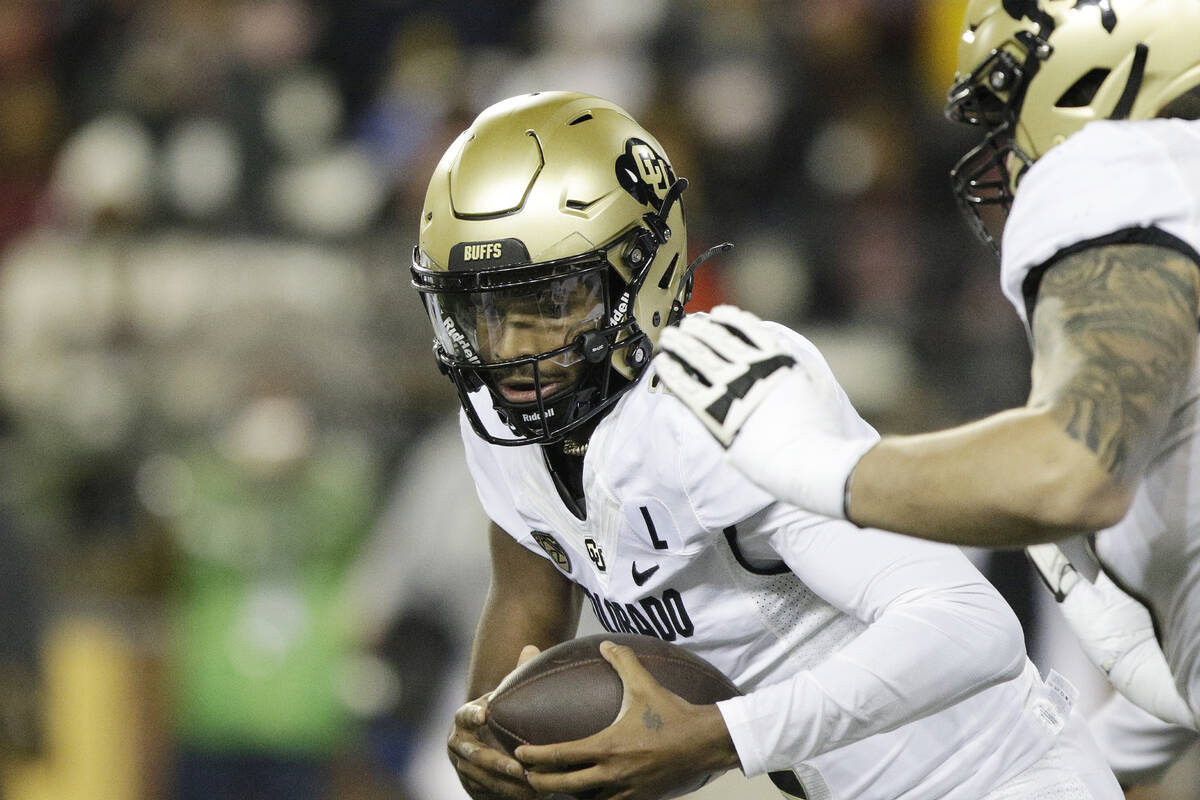 Colorado quarterback Shedeur Sanders, center, carries the ball during the first half of an NCAA ...