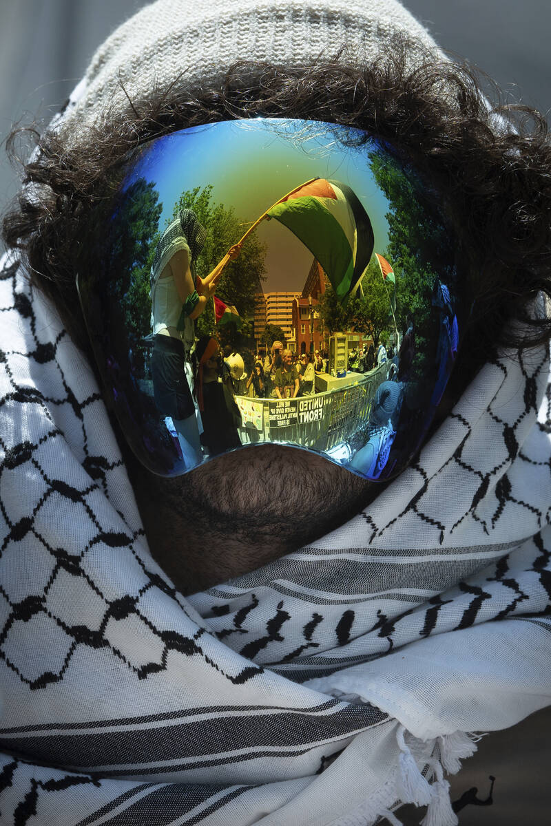 A Palestinian flag is reflected in a demonstrator's mask as students protest the Israel-Hamas w ...
