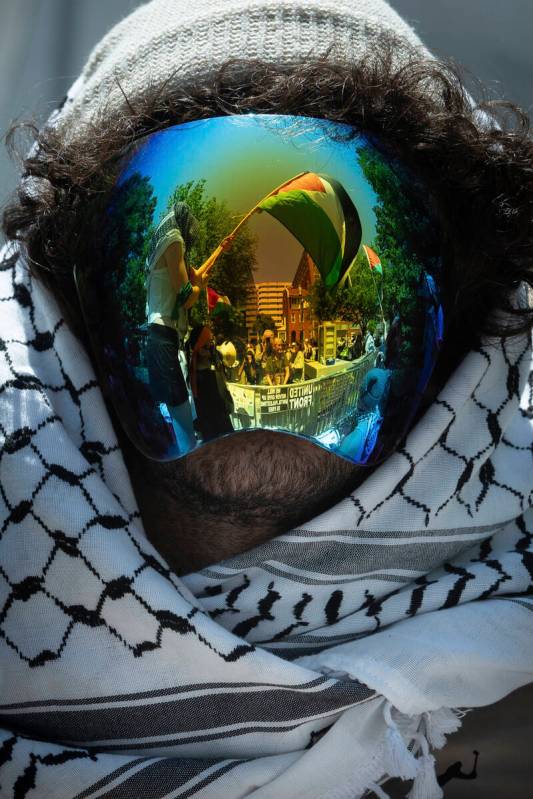 A Palestinian flag is reflected in a demonstrator's mask as students protest the Israel-Hamas w ...