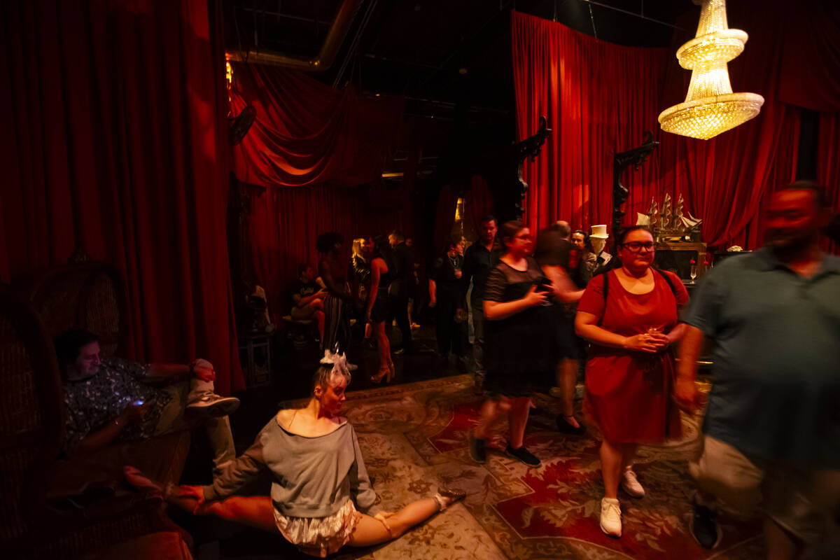 Contortionist and aerialist Cheryl Birch, left, stretches as guests walk by during the closing ...