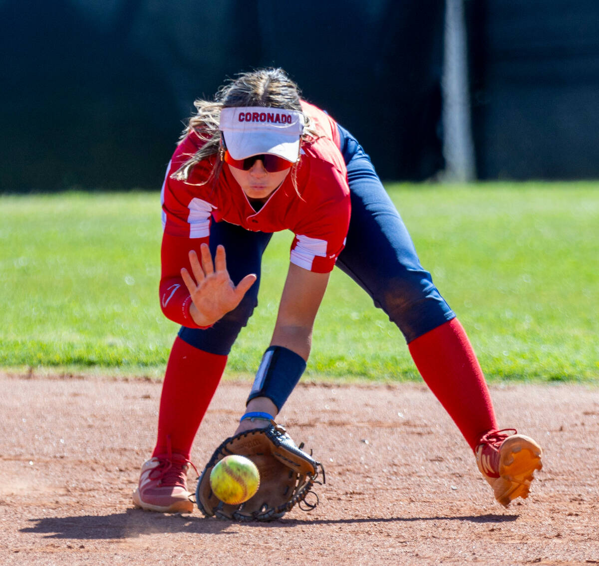 Coronado infielder Bailey Goldberg (1) scoops up a ground ball before a throw to first base and ...
