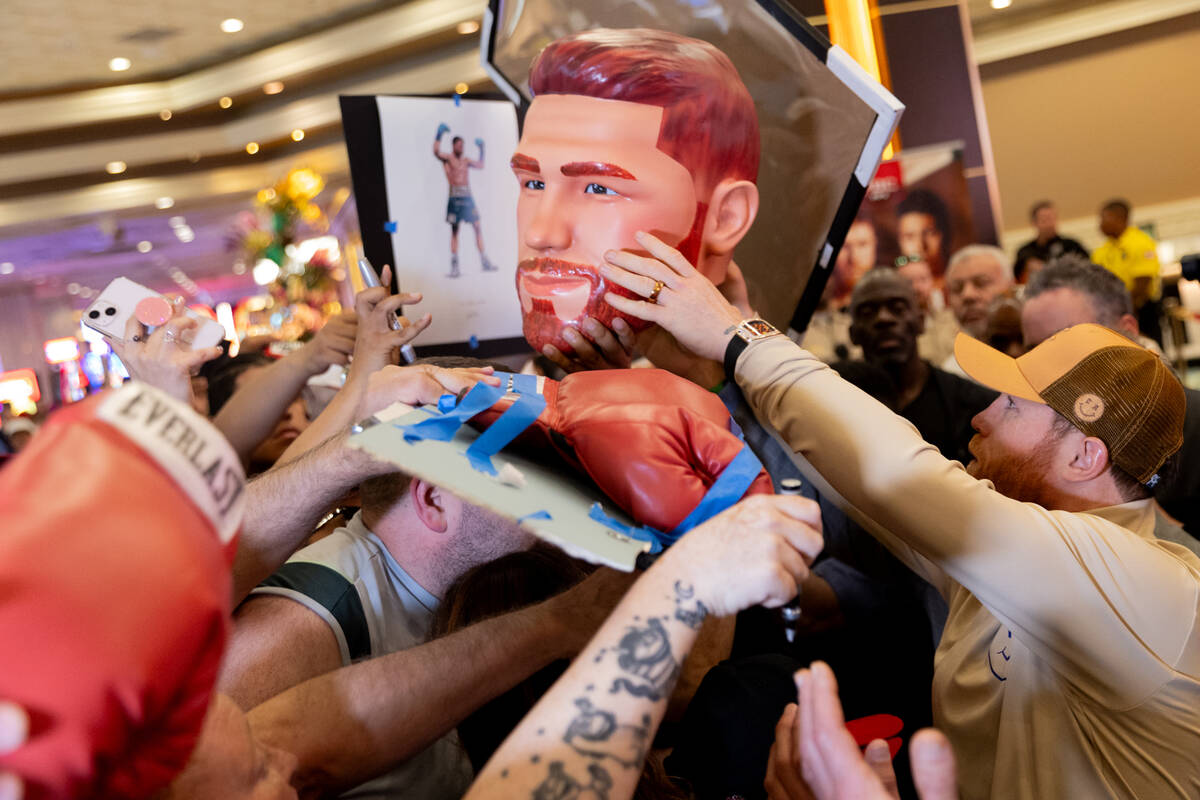 Canelo Alvarez reaches to sign a likeness of his head for a fan after arriving to MGM Grand ahe ...
