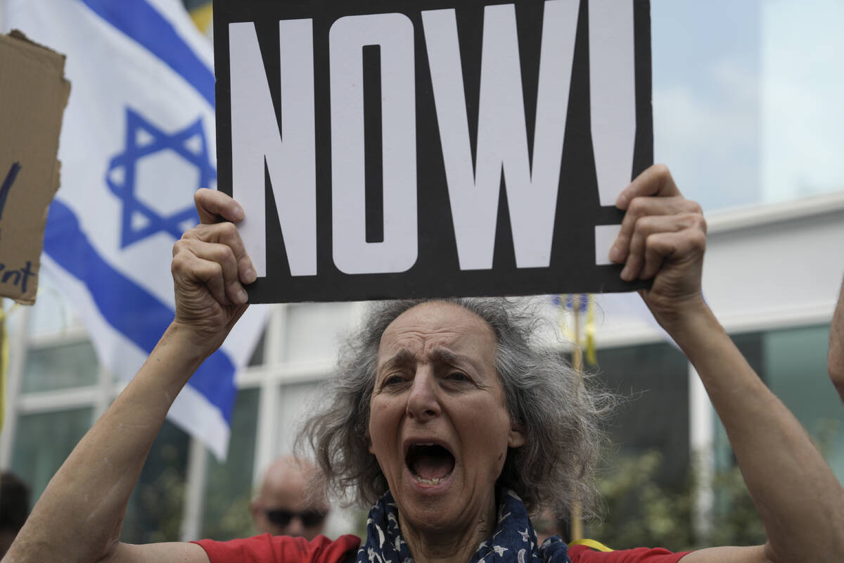 A woman holds a banner and shouts slogans with families and supporters of Israeli hostages held ...