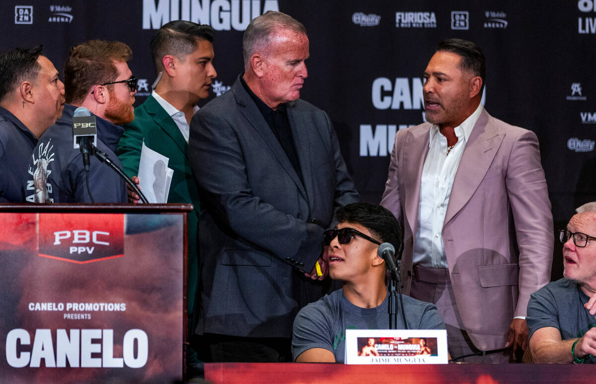 Boxer Canelo Alvarez attempts to get to boxing promotor Oscar De La Hoya as they trade verbal i ...